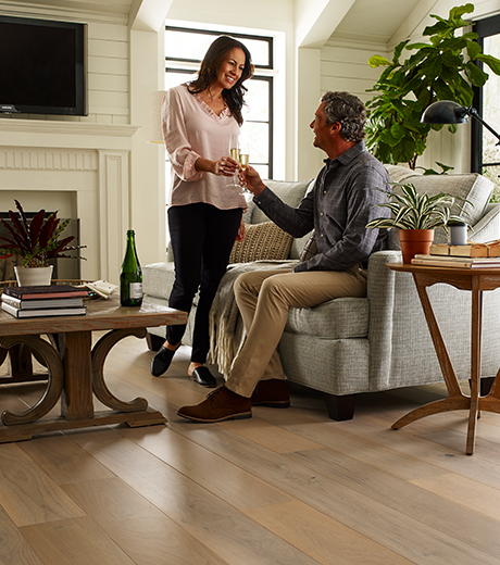 Couple sharing drinks in living room with wood-look luxury vinyl flooring from The Carpet Yard in McLean, VA