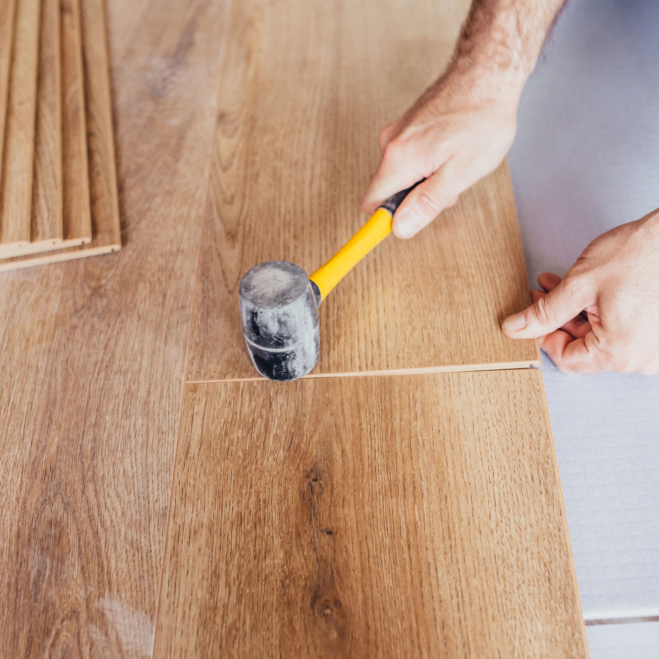 Person installing engineered hardwood flooring - Floor refinishing and installation services from The Carpet Yard in McLean, VA