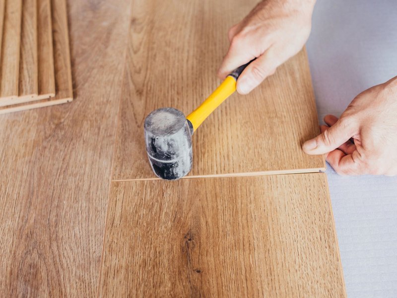 Person installing engineered hardwood flooring - Floor refinishing and installation services from The Carpet Yard in McLean, VA