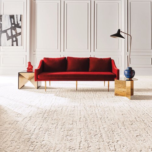 A red couch on a white capet in the middle of the room from The Carpet Yard, your hometown flooring store, in McLean